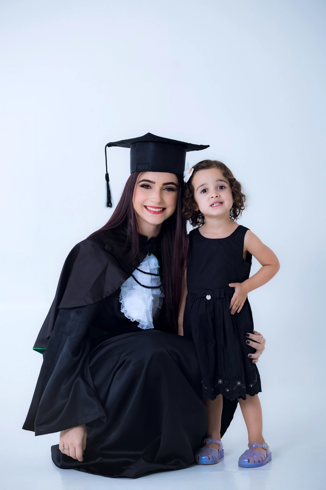 Formanda agachada abraçando a irmã caçula, ambas sorrindo