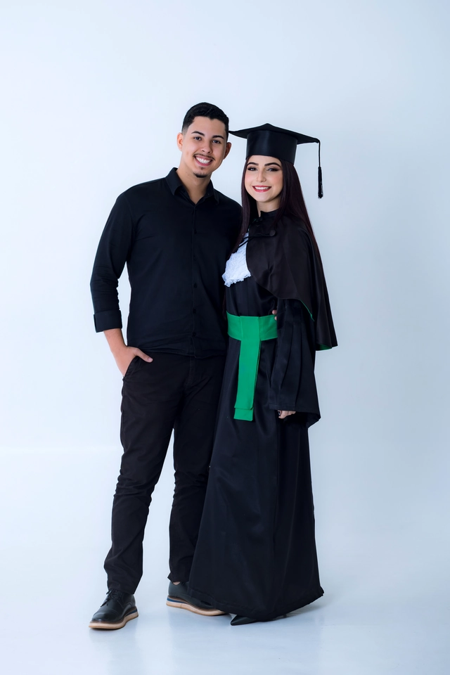 Formanda de beca ao lado do namorado, os dois sorrindo