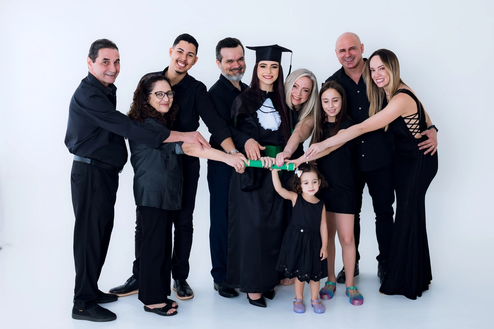 Família reunida em círculo com as mãos apoiadas sobre o diploma da formanda