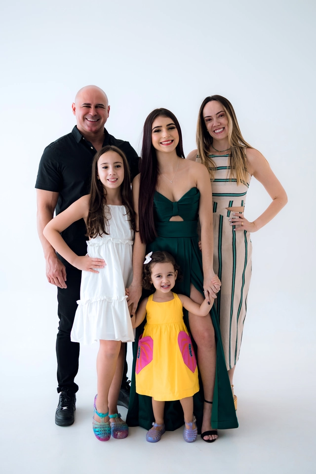 Formanda de vestido verde ao lado dos pais e das duas irmãs