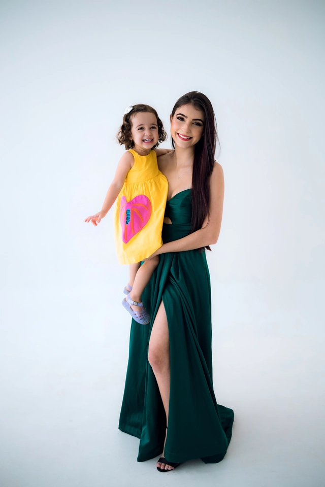 Formanda de vestido verde segurando a irmã caçula no colo