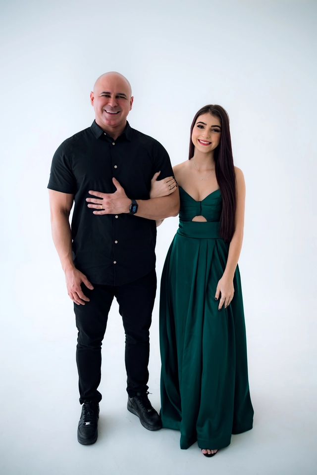 Formanda de vestido verde abraçada ao pai, retrato em estúdio