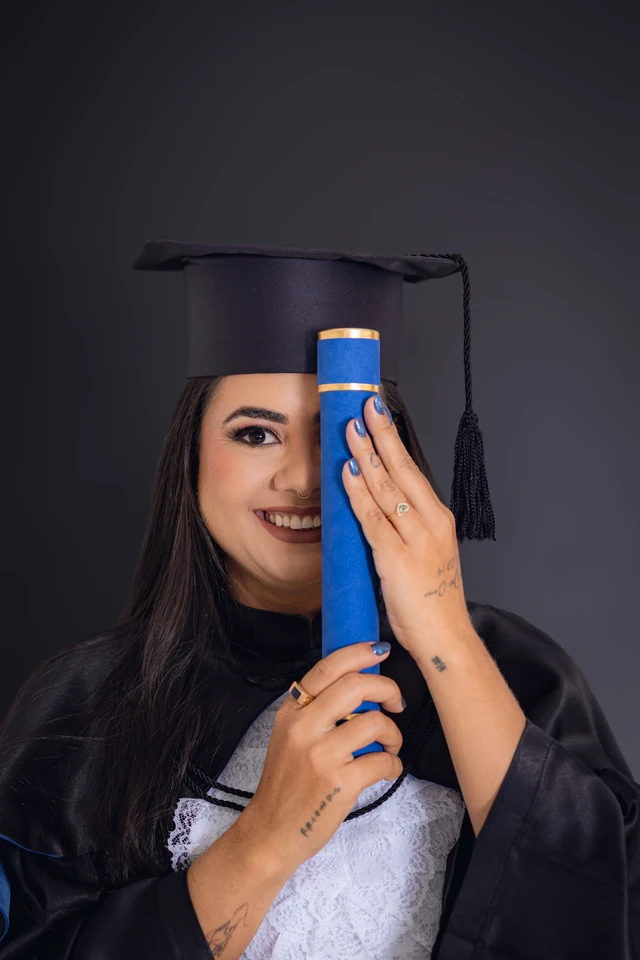 Formanda cobrindo o olho com o diploma, retrato de formatura em estúdio