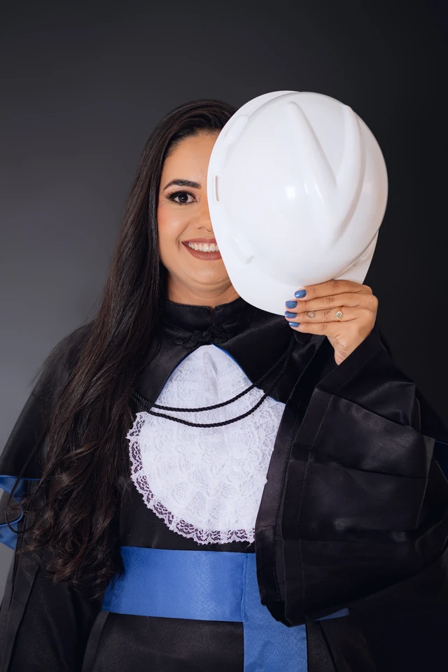 Formanda sorrindo com o capacete de engenharia cobrindo parte do rosto