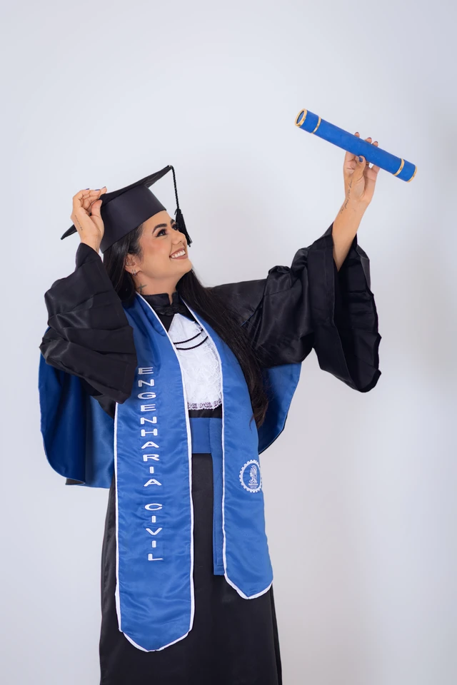 Formanda comemorando, erguendo o capelo e o diploma