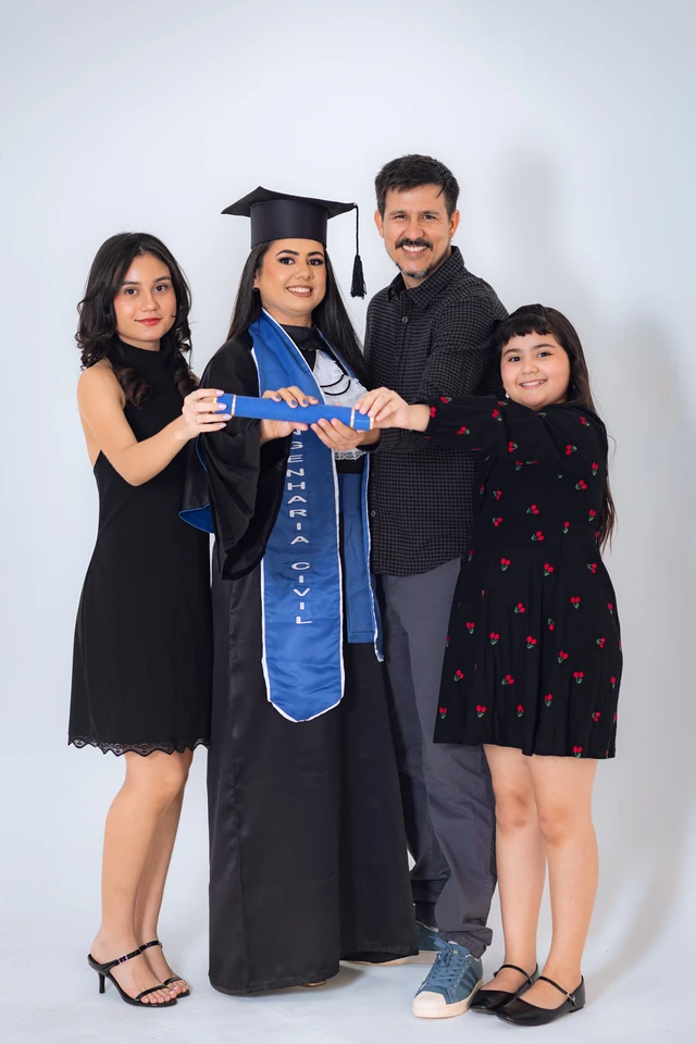 Formanda com os pais e a irmã mais nova, todos segurando o diploma