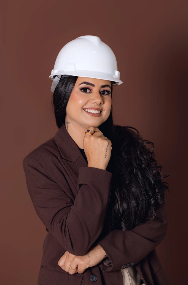 Retrato da formanda com capacete de engenharia e blazer, fundo marrom