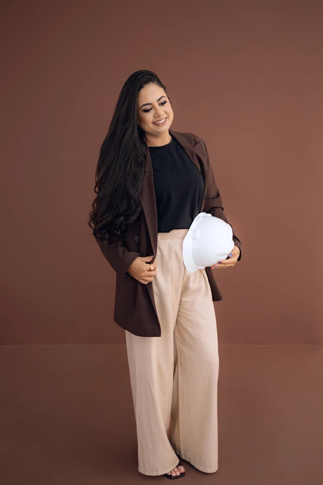 Formanda de corpo inteiro, look profissional de engenharia, fundo marrom