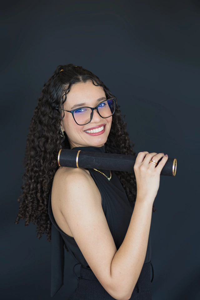 Formanda de Veterinária com o diploma apoiado no ombro, retrato em estúdio