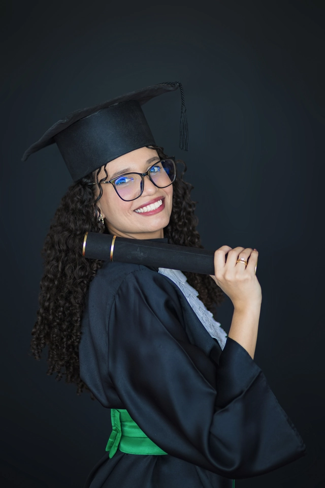Formanda de perfil com o diploma apoiado no ombro, fundo preto