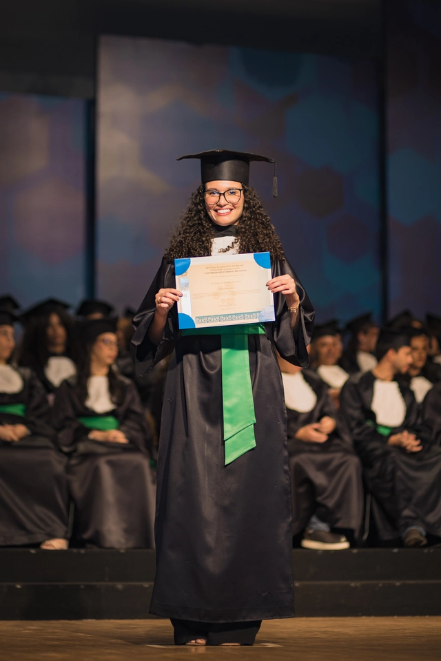 Formanda no palco da colação de grau da UFG, segurando o certificado