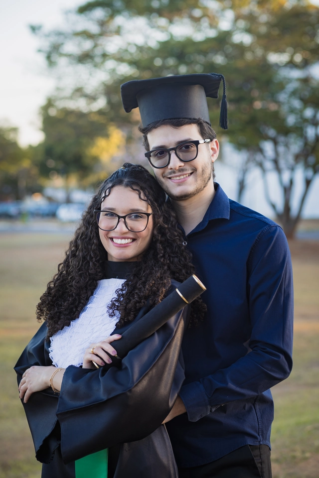 Formanda ao lado de um amigo, comemorando a formatura no campus